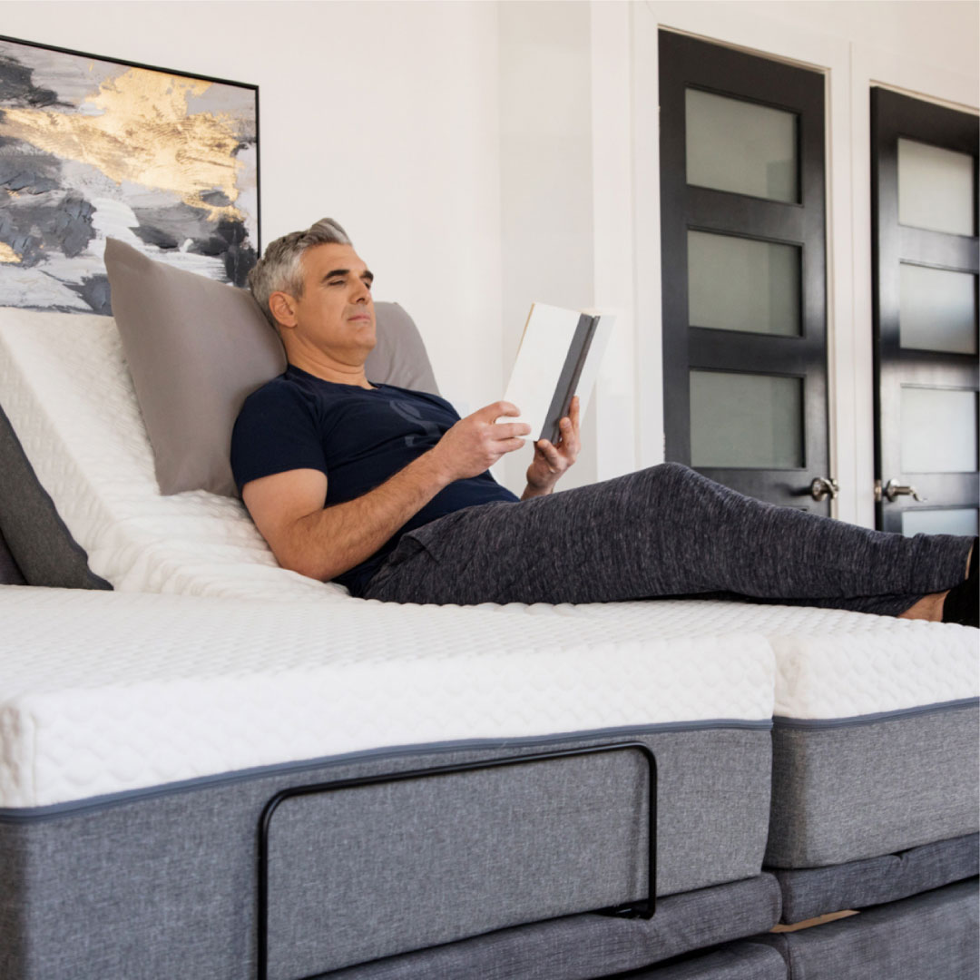 Senior mand laying on adjustable bed reading a book