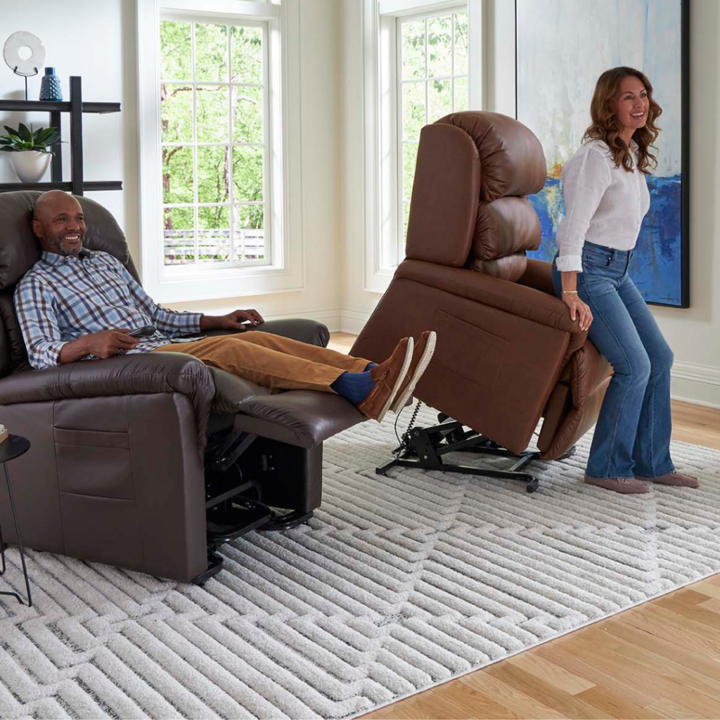Man reclined in dark brown leather power lift recliner on left and woman using stand function on medium brown leather power lift recliner on right