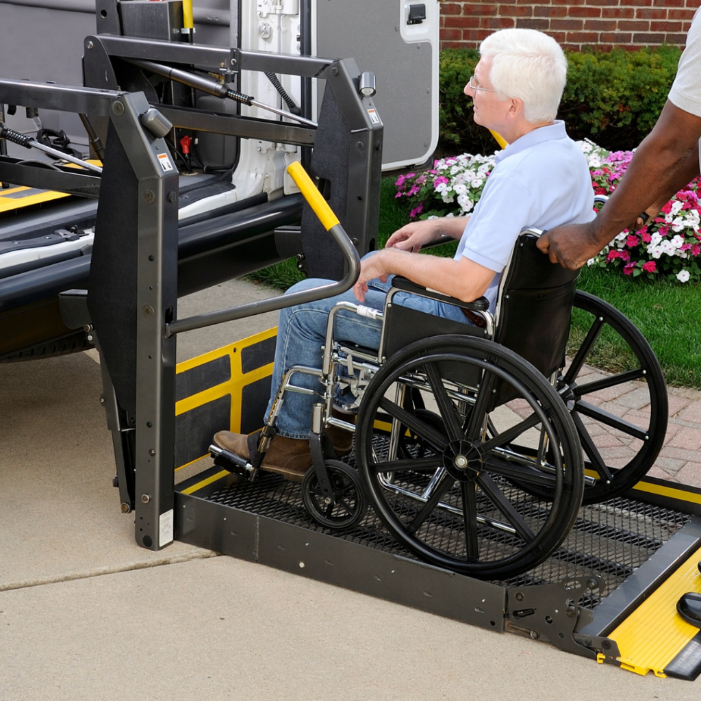 Senior man in manual wheelchair being pushed by man onto accessible vehicle ramp at rear entry