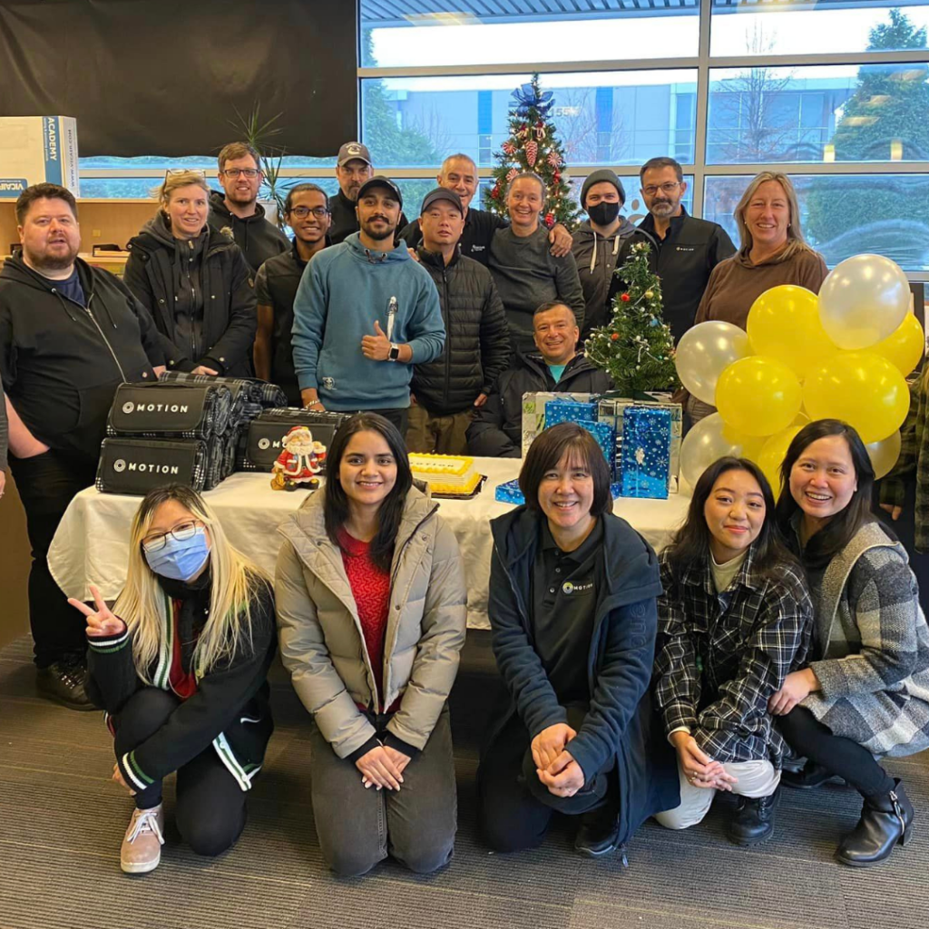 Motion Burnaby team gathered around a table during 5 Days of Caring with Motion-branded gifts and yellow ballons
