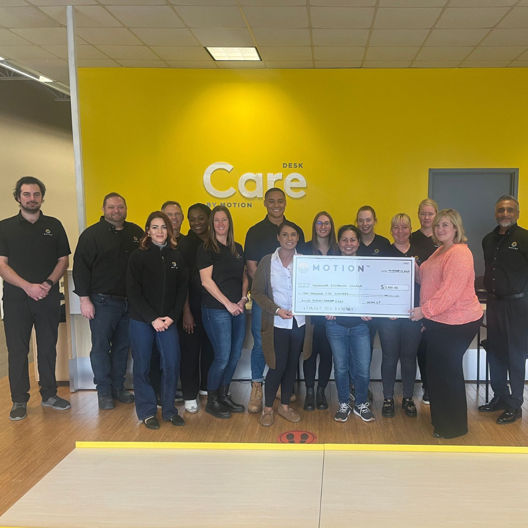 Members of the Motion Mississauga team pictured with a representative from Muscular Dystrophy Canada holding up a novelty cheque to display a $2500 donation to the charity for Giving Tuesday.