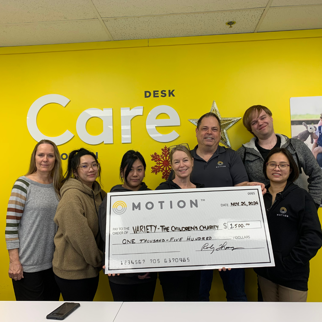 Members of the Motion Calgary team pictured with a representative from Variety the Children's Charity holding up a novelty cheque to display a $1500 donation to the charity for Giving Tuesday.