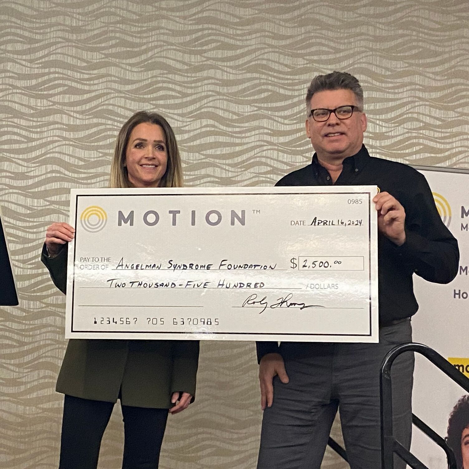 Motion VP Jeff Preston pictured with a representative from the Angelman Syndrome Foundation holding a novelty cheque to display a $2500 donation to the charity.