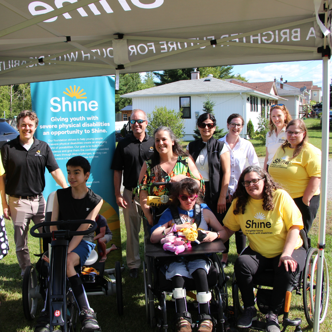 Shine Foundation event in Sudbury featuring members of the Shine and Motion teams alongside a Shine Foundation Dream recipient and his family. The Shine recipient is seated in his new adaptive bike.