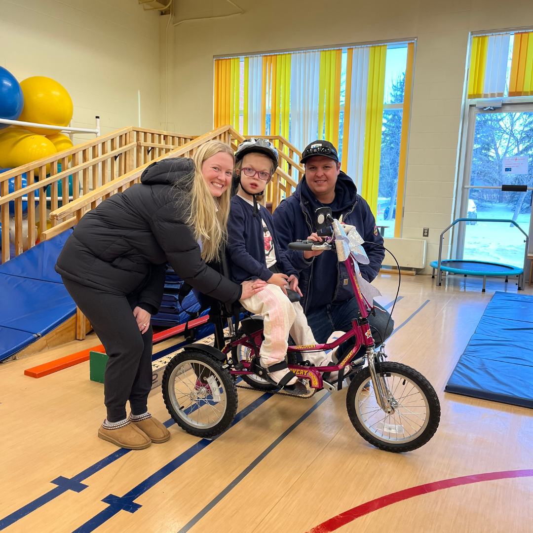 Anika in her new tricycle with her parents.