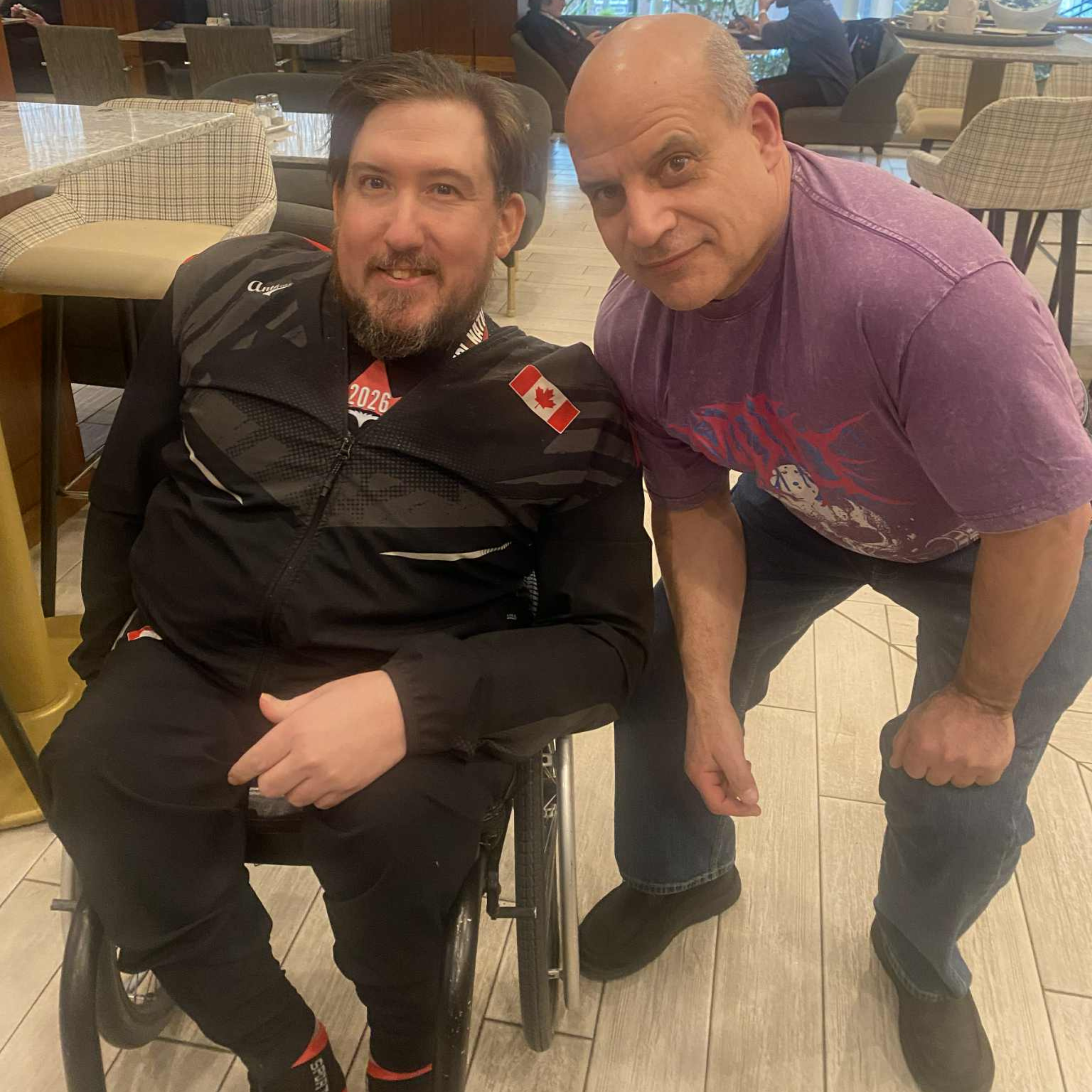 Tyler posing with a para lifter who is a wheelchair user.