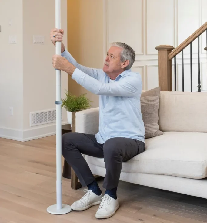 A man in a blue shirt using the UPole from Healthcraft to get off of his couch.